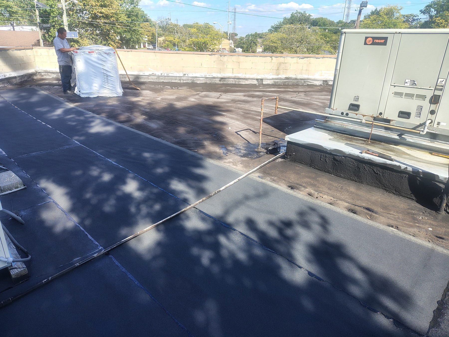 Roofing material laid near rooftop equipment, with additional material on site