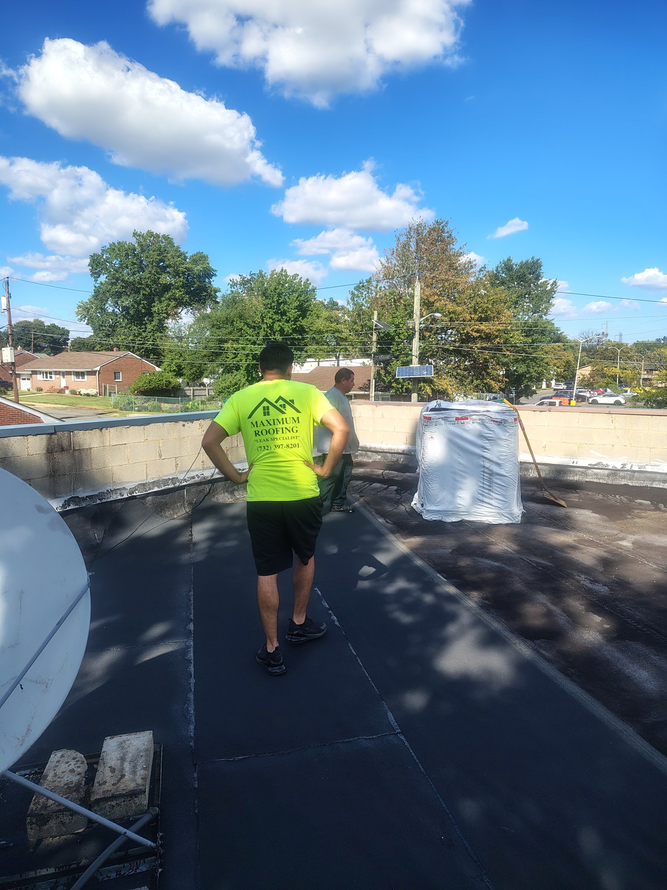 Maximum Roofing crew member beside roofing material on the commercial roof