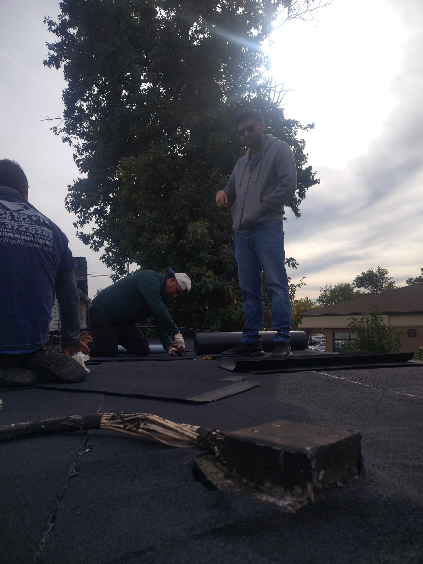 Crew members working with rolls of roofing material on the Richmond Hill Road project