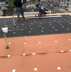 Crew members installing roofing layers on a flat roof.