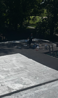Roofing work in progress with rolled material and roof layers visible.